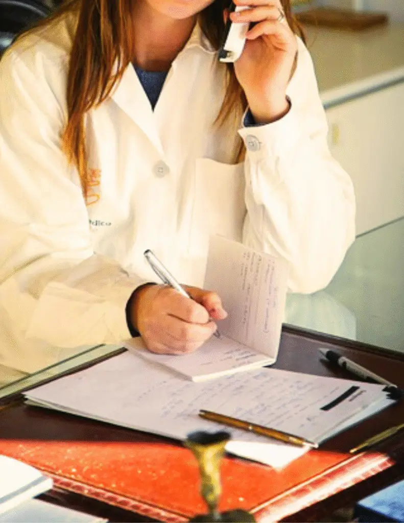 Pharmacist taking notes and speaking on phone to assist patients with prescriptions