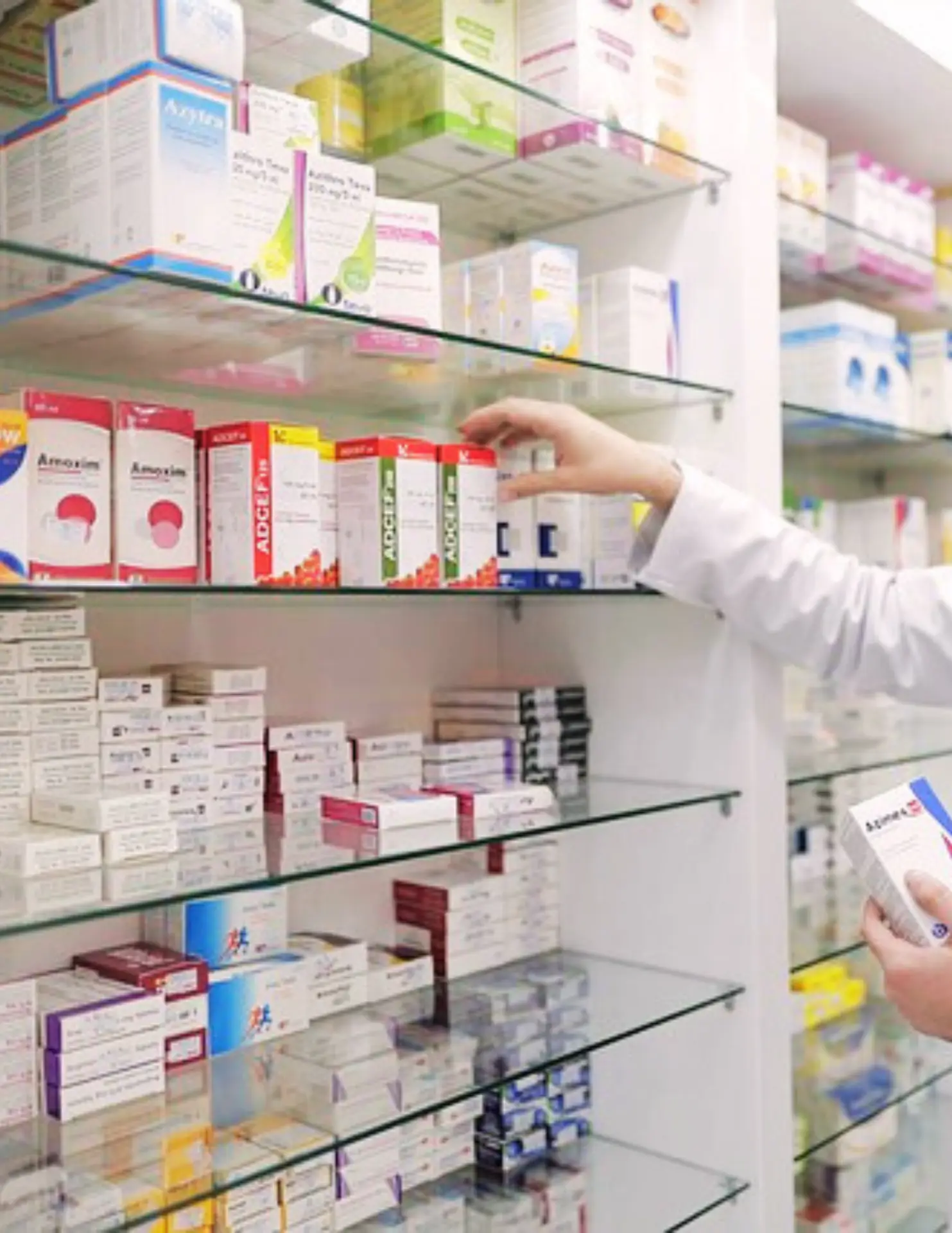 Pharmacist selecting medication from pharmacy shelves filled with prescription and over-the-counter medicines
