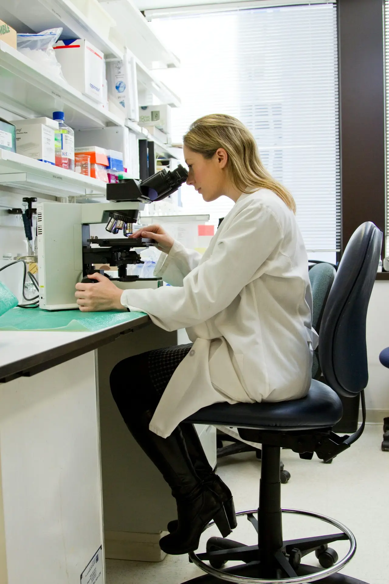 Female pharmacist examining sample through microscope in a pharmacy lab
